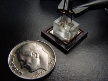 A photo of a small electronic device next to a dime to show scale