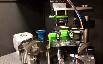 A photo of the centrifugation device with wires, a rotor, a motor, and the lens and filters