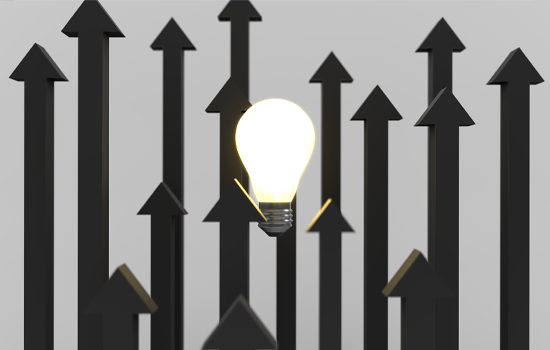 A lit up lightbulb with many black arrows pointing upwards.