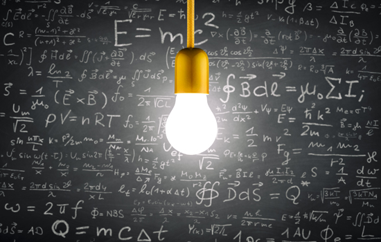 A lit up lightbulb in front of a chalkboard with many equations written on it