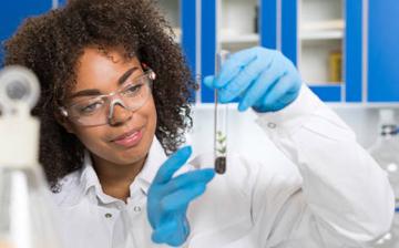 young woman in lab looking at test tube