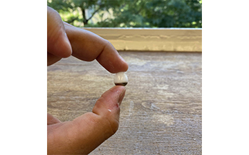 The robotic pill being held between the middle finger and thumb