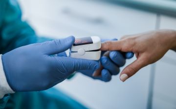A pulse oximeter being applied to a person with dark skin