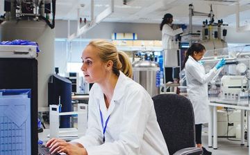 Young female scientist works at a computer in a lab