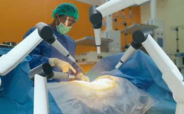 Photo of a doctor during surgery with robotic arms in frame