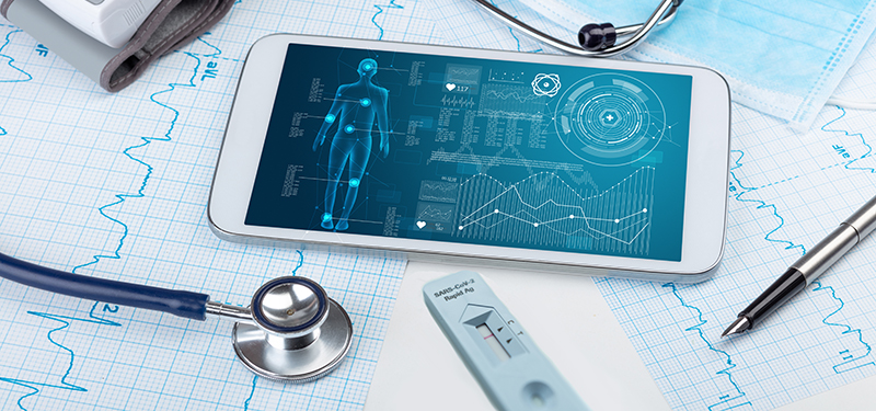 Table surface with EKG graphs, stethoscope, rapid test, smart phone and pen