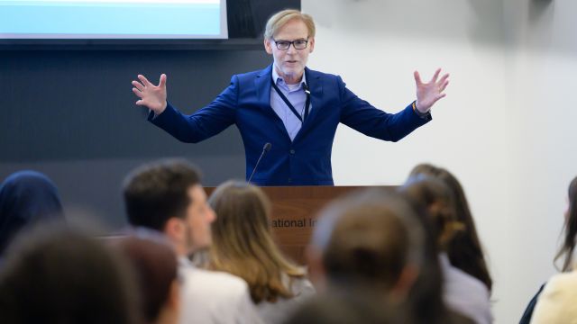 Bruce Tromberg standing at a lecturn speaks to a seated audience 