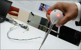An image of the probe, a slender stick with a white bulb on top with a red light.