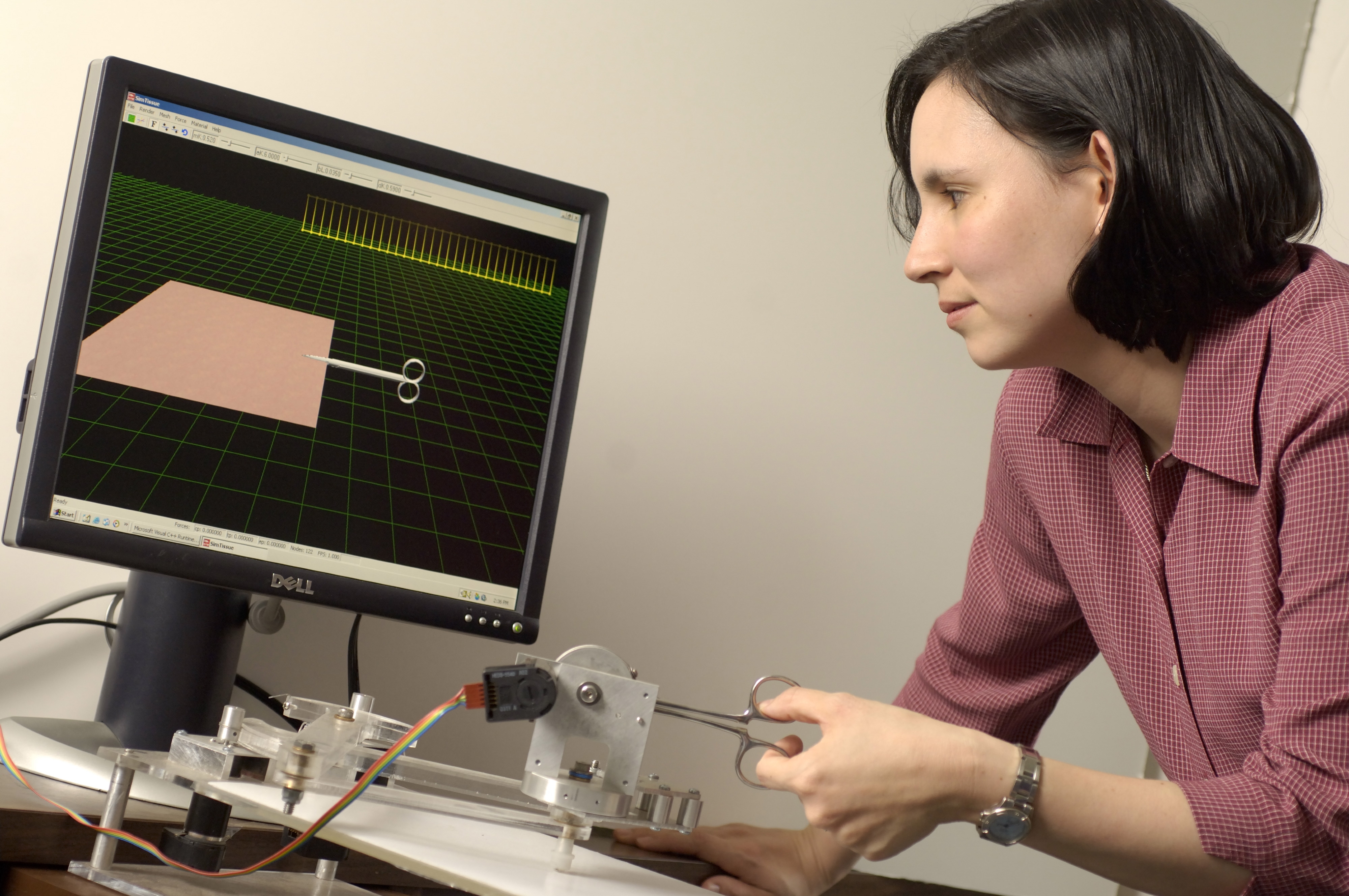 La doctora Allison Okamura, investigadora de la Universidad Johns Hopkins, demuestra un aparato háptico que interactúa con un ambiente virtual para mostrar al usuario las fuerzas cortantes.Cortesía de Will Kirk.