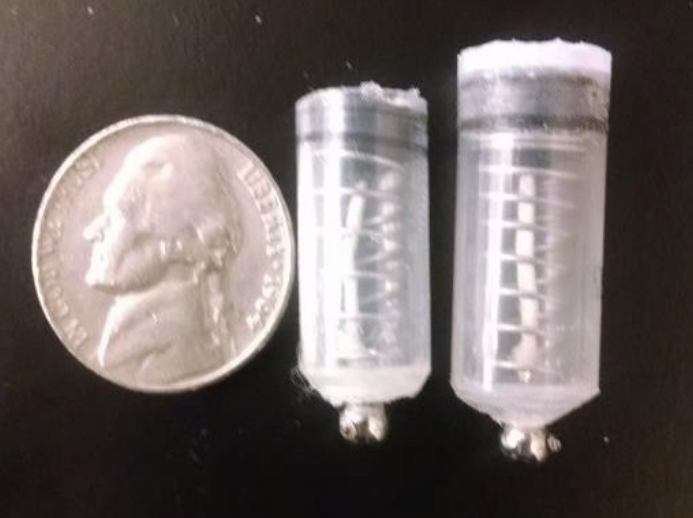 Photo of two prototypes of the smart pill next to a nickel for scale.