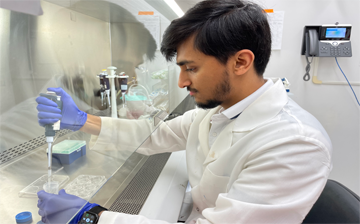 Aasim Hawa pipettes fluid in a biosafety cabinet.