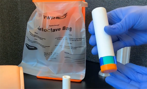 A gloved hand holds the EpicPen epinephrine autoinjector