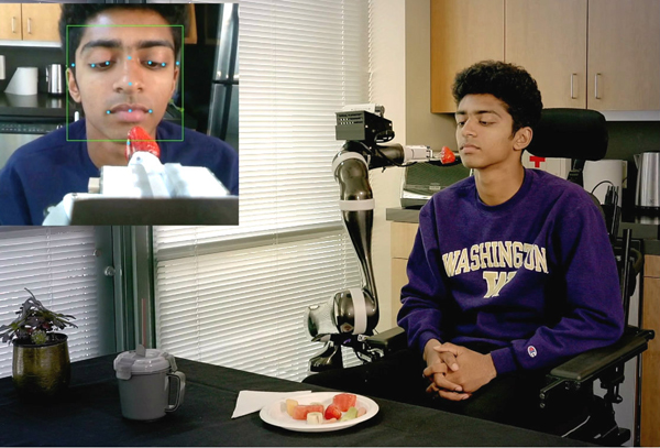 ADA robot presents strawberry to volunteer
