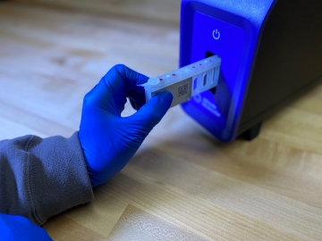 gloved hand placing cartridge in a blue instrument