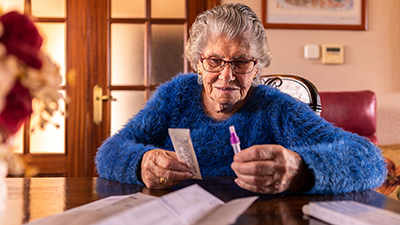 An elderly woman holds COVID-19 test kit parts