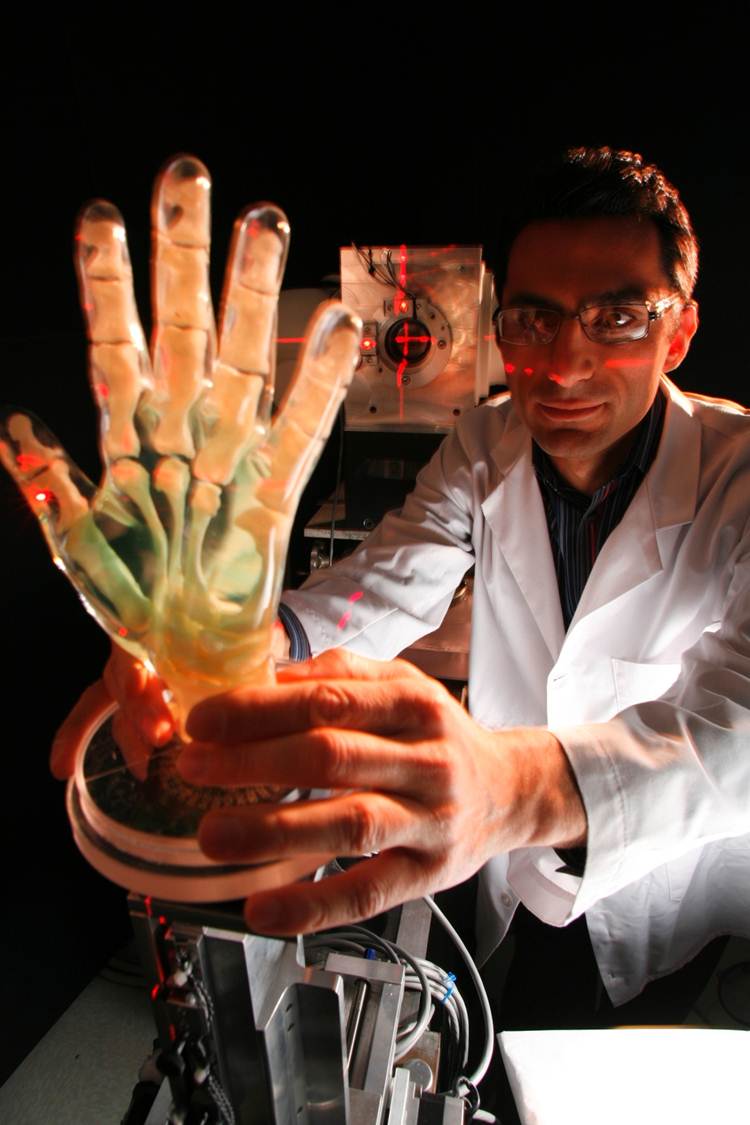 Una foto de un investigador sosteniendo una mano robótica transparente con alambres que la atraviesan