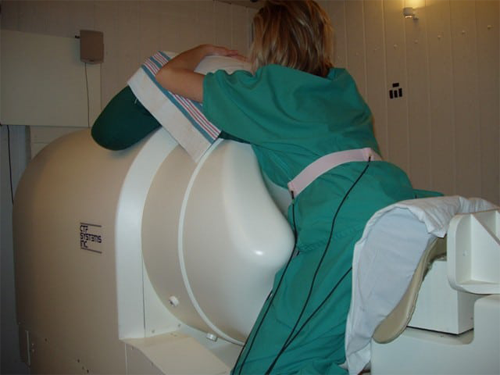 A pregnant person rests their abdomen on the SQUID Array for Reproductive Assessment (SARA)