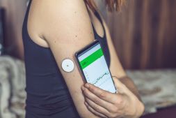 Mujer checando el nivel de glucosa con sensor y teléfono móvil