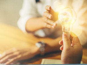 person handing an illuminated light bulb to another person