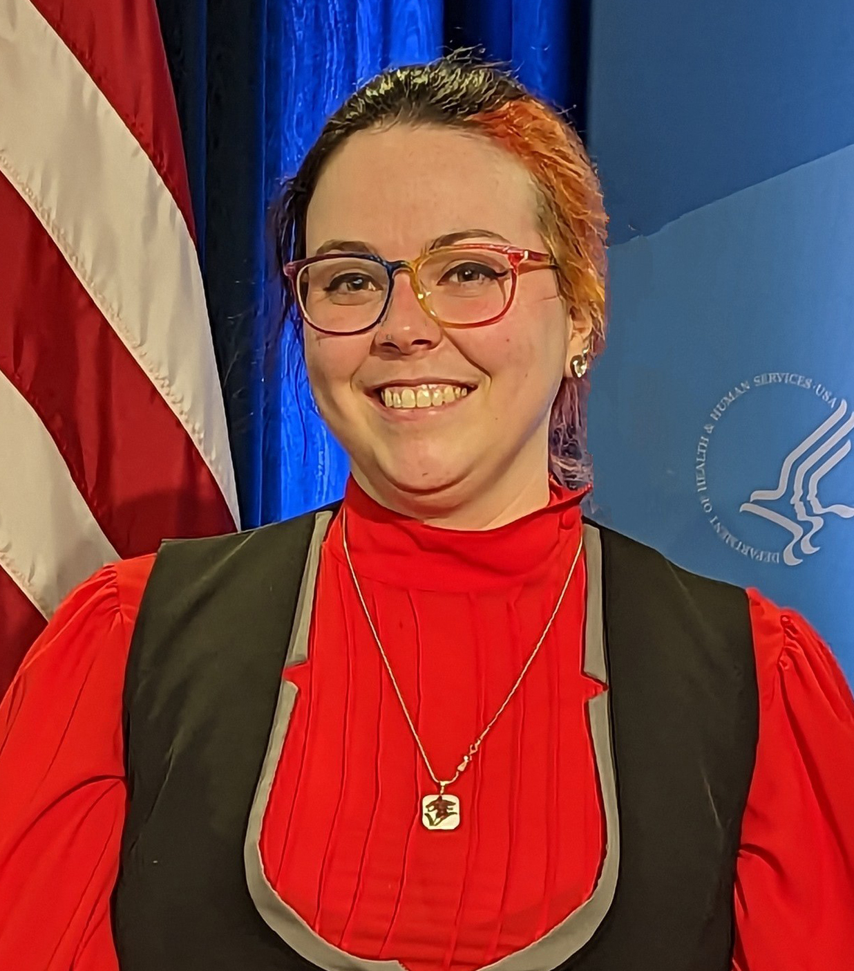 smiling person with U.S. flag in background