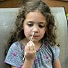 Girl uses nasal swab to collect a sample for a COVID-19 test.