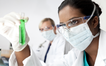 woman scientist studying a test tube full of green liquid