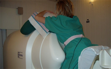 A pregnant person rests their abdomen on the SQUID Array for Reproductive Assessment (SARA)