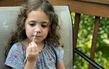 Girl uses nasal swab to collect a sample for a COVID-19 test.