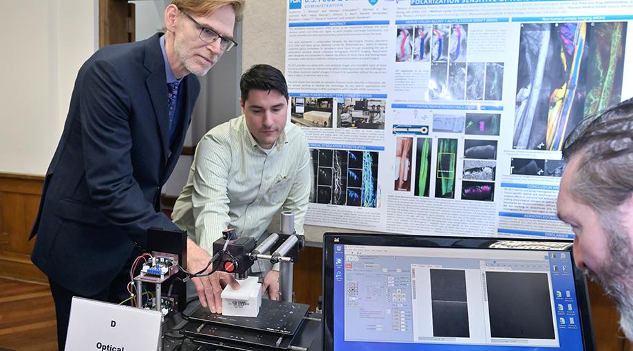 NIBIB Director Dr. Bruce Tromberg helps demonstrate an optical imaging system developed to noninvasively image peripheral nerves. Guillermo Monroy helps guide Dr. Tromberg’s hand while Daniel Hammer observes the image on the screen.